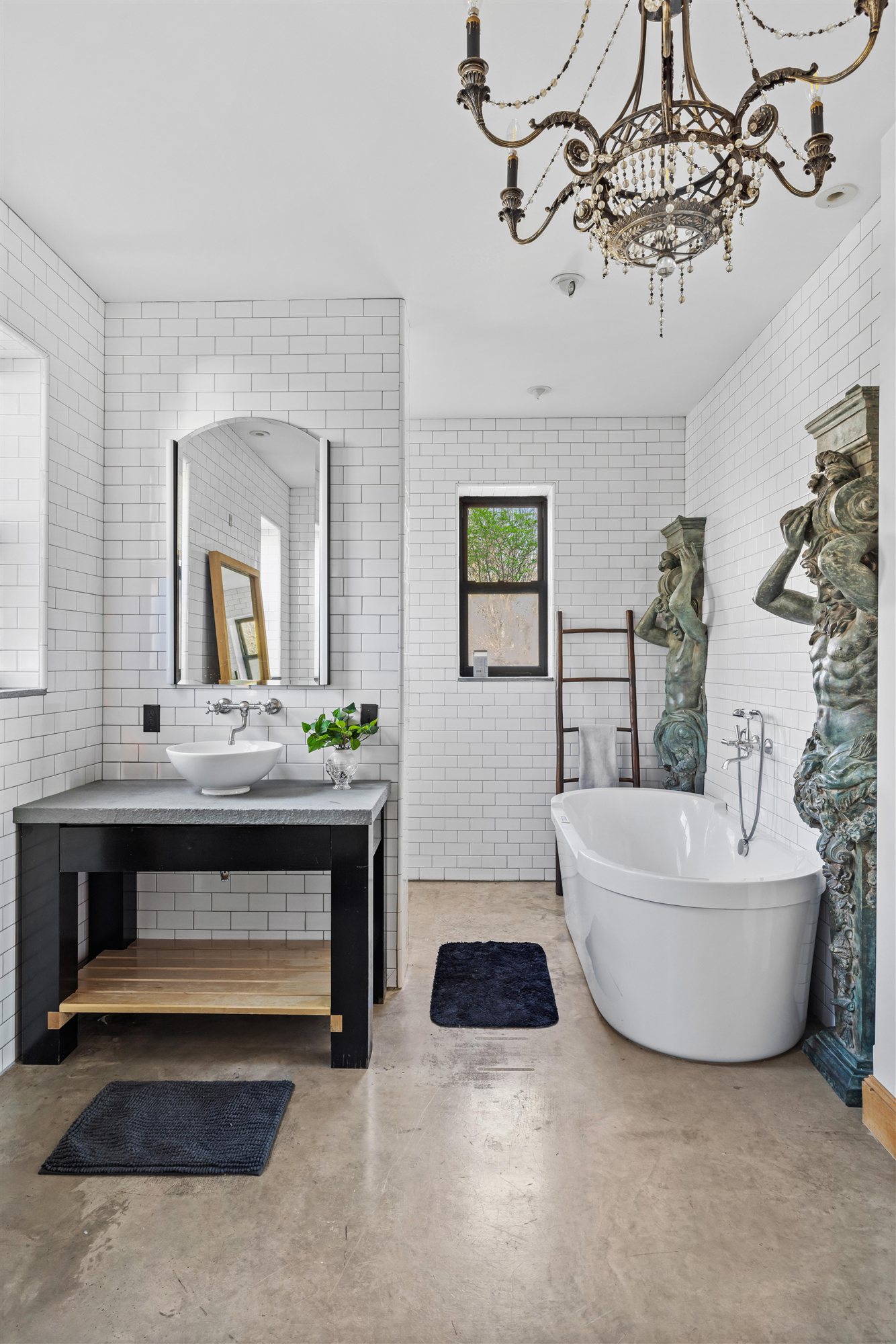 Freestanding soaking tub beneath a chandelier
