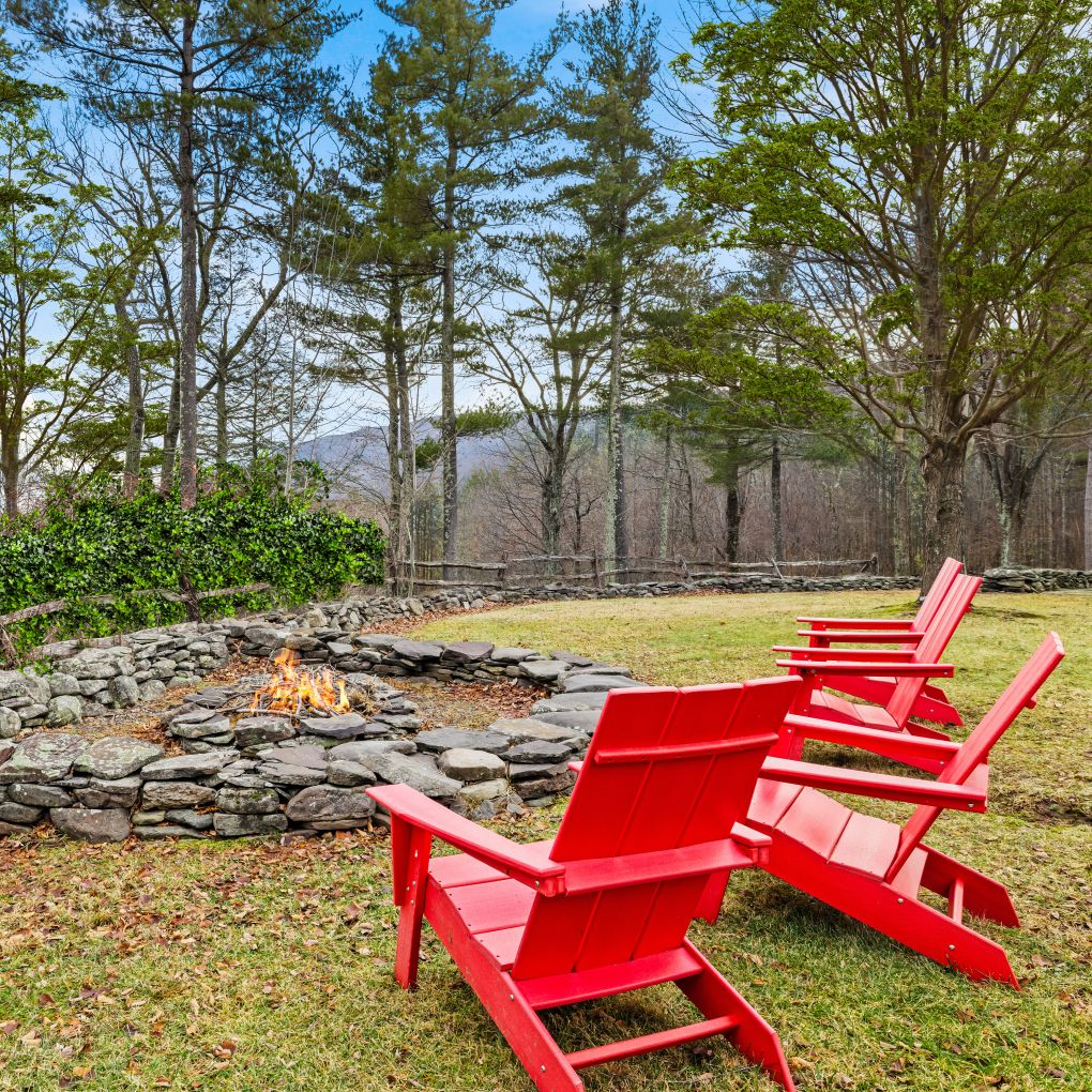 Stone firepit with red Adirondack chairs and mountain views