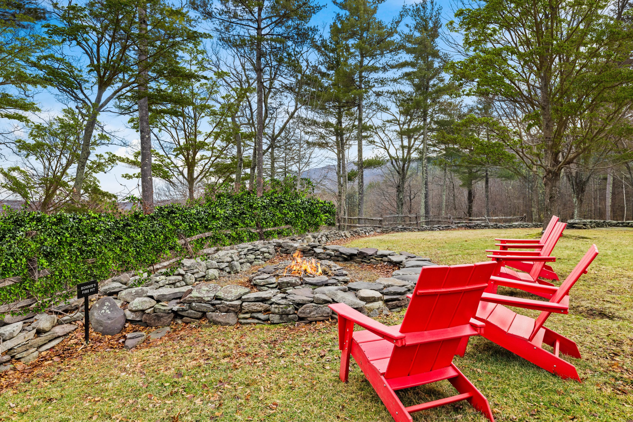 Bonnie's Fire Pit at Crow's Nest Retreat — red Adirondack chairs around a stone firepit with Catskill mountain views