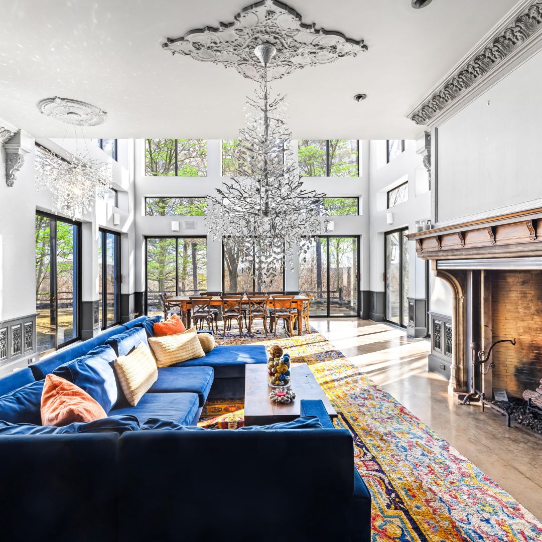The Great Room — blue velvet sectional, antique European fireplace, and two-story windows